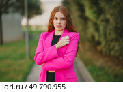 In an outdoor setting that showcases lush greenery and vibrant colors, a stylish young woman, dressed in a striking pink blazer, poses confidently, exuding an air of elegance and modern femininity. A Confident Young Woman Dressed in a Pink Blazer is Posing Outdoors with Style and Grace. Стоковое фото, агентство Ingram Publishing / Фотобанк Лори