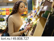 A woman intently examines a variety of fresh produce in a grocery store, which showcases her dedication and focus on selecting healthy food options for her and her familys wellbeing. A woman is shopping for fresh and healthy produce at her local grocery store today. Стоковое фото, агентство Ingram Publishing / Фотобанк Лори