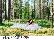 Young woman is reading a book in the forest lying on a mattress. The girl relaxing in nature. Стоковое фото, агентство Ingram Publishing / Фотобанк Лори