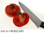Cutting white plastic board with a knife and tomato isolated on a white background. Стоковое фото, агентство Ingram Publishing / Фотобанк Лори
