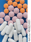 Macro view of white pink and orange pills on blue background. Стоковое фото, агентство Ingram Publishing / Фотобанк Лори