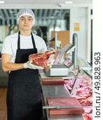 Positive young salesman demonstrating piece of meat in butcher shop. Стоковое фото, фотограф Яков Филимонов / Фотобанк Лори