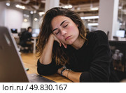 A woman is sleeping on a desk with a laptop on it. Стоковое AI-изображение, AI-художник Ярославский Максим / Фотобанк Лори