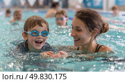 A woman is teaching a child how to swim. Стоковое AI-изображение, AI-художник Ярославский Максим / Фотобанк Лори