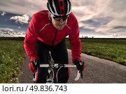 Cyclist on road bike through a asphalt road and blue sky with clouds. Стоковое фото, агентство Ingram Publishing / Фотобанк Лори