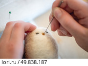 Close-up of artist's hands using a special needle to create a needle felted animal toy from wool roving, demonstrating the delicate process of needle felting. Стоковое фото, фотограф Ольга Ильина / Фотобанк Лори