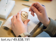 Close-up of artist's hands using a special needle to create a needle felted animal toy from wool roving, demonstrating the delicate process of needle felting. Стоковое фото, фотограф Ольга Ильина / Фотобанк Лори