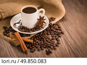 Coffee cup with burlap sack of roasted beans on rustic table. Стоковое фото, агентство Ingram Publishing / Фотобанк Лори