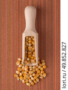 Top view of wooden scoop with corn against red vinyl background. Стоковое фото, агентство Ingram Publishing / Фотобанк Лори