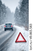 Winter Road Hazard With Warning Triangle and Car in Snowfall on a Remote Highway. Стоковое AI-изображение, AI-художник Юлия Гапеенко / Фотобанк Лори