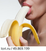 Young woman biting banana isolated on white. Стоковое фото, агентство Ingram Publishing / Фотобанк Лори