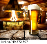 Beer on wooden table in bar with furnace. Стоковое фото, агентство Ingram Publishing / Фотобанк Лори