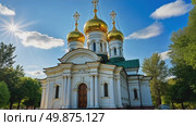 A majestic white Orthodox church with golden domes stands in a park with colorful autumn trees under a blue sky with clouds. Стоковое AI-видео, аниматор Sergey Grishin / Фотобанк Лори