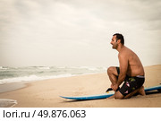 Surfer tying his surfboard’s leach on the beach. Стоковое фото, агентство Ingram Publishing / Фотобанк Лори