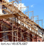 Residential construction in the process of being built as a real estate structure with metal scaffolding as a business symbol of economic investment rise with financial growth in a healthy economy. Стоковое фото, агентство Ingram Publishing / Фотобанк Лори