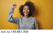 A woman in a sweater stands confidently with her right arm is raised in a fist pump, indicating triumph or celebration, young happy black girl dancing in studio. Стоковое AI-видео, аниматор Sergey Grishin / Фотобанк Лори