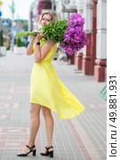 A beautiful elderly woman with a bouquet of flowers walks through the streets of the city. Age model blonde in full growth. A woman in her fifties in a beautiful dress. Стоковое фото, фотограф Лазаренко Светлана / Фотобанк Лори