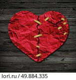 Heart repairing therapy as a red crumpled paper shaped as a torn love icon that has been taped together as a metaphor for therapy and reconciliation on rustic old wood also a symbol of medical cardiovascular health care surgery due to illness. Стоковое фото, агентство Ingram Publishing / Фотобанк Лори