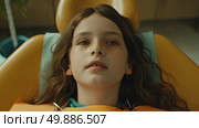 A young girl is seated comfortably in a dentist chair for a check-up, surrounded by dental tools and equipment. Стоковое AI-изображение, AI-художник Данила Большаков / Фотобанк Лори