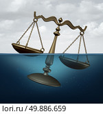 Legal trouble concept or justice problems symbol as a scale of justice drowning in water as a metaphor for law or regulation problems. Стоковое фото, агентство Ingram Publishing / Фотобанк Лори