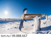 Snowboard leaning on a wood rail on a winter snow covered mountainside and sun shine in blue sky. Стоковое фото, агентство Ingram Publishing / Фотобанк Лори