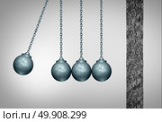 Momentum concept as a group of wrecking balls as a newton cradle pendulum symbol facing a cement wall as a business metaphor for applying a tream strategy to break an obstacle with 3D illustration elements. Стоковое фото, агентство Ingram Publishing / Фотобанк Лори