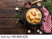 Meat stewed with carrots in sauce and spices in cast iron pan on dark wooden rustic background top view flat lay. Стоковое фото, агентство Ingram Publishing / Фотобанк Лори
