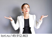 Asian business woman raising her hands on both sides on a gray background. Стоковое фото, агентство Ingram Publishing / Фотобанк Лори
