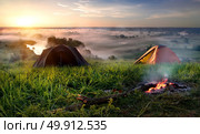 Tents and bonfire in steppe near river at sunrise. Стоковое фото, агентство Ingram Publishing / Фотобанк Лори