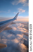 View of the Airplane Wing Above Fluffy Clouds During Sunset With Dramatic Sky Colors. Стоковое AI-изображение, AI-художник Юлия Гапеенко / Фотобанк Лори