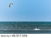 Kitesurfer riding ocean waves on a bright sunny day. Стоковое фото, агентство Ingram Publishing / Фотобанк Лори