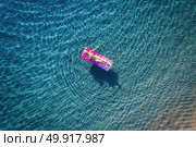 Aerial view of young woman swimming on the pink inflatable mattress in the transparent turquoise sea in Ichmeler,Turkey. Summer seascape with girl, azure water in the morning. Top view from drone. Aerial view of young woman swimming on the pink inflatable mattr. Стоковое фото, агентство Ingram Publishing / Фотобанк Лори