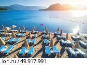 Aerial view of swimming woman on the air mattress in the sea against mountains at sunset. Summer seascape with girl, blue water and sandy beach with chaise-lounges. Top view. Travel in Icmeler, Turkey. Aerial view of swimming woman on the air mattress. Стоковое фото, агентство Ingram Publishing / Фотобанк Лори