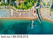 Aerial view of transparent turquoise sea, beautiful sandy beach with colorful chaise-lounges, boats, green trees, hotels, buildings at sunset in Icmeler, Turkey. Summer seascape Top view from drone. Стоковое фото, агентство Ingram Publishing / Фотобанк Лори