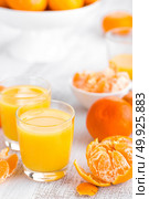 Tangerines, peeled tangerines and tangerine juice in glass. Mandarine juice. Стоковое фото, агентство Ingram Publishing / Фотобанк Лори