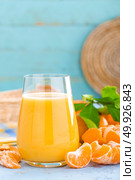 Tangerines, peeled tangerines and tangerine juice in glass. Mandarine juice and fresh fruits with leaves. Стоковое фото, агентство Ingram Publishing / Фотобанк Лори