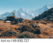 Standing man on the stone and looking on amazing mountains at sunset. Landscape with traveler, high rocks with snowy peaks, grass, trees in autumn in Nepal. Lifestyle, travel. Trekking in Himalayas. Стоковое фото, агентство Ingram Publishing / Фотобанк Лори