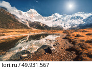 Beautiful scene with high rocks with snow covered peaks, stones in mountain lake, reflection in water, blue sky in sunset. Nepal. Amazing landscape with Himalayan mountains at bright sunny day. Nature. Стоковое фото, агентство Ingram Publishing / Фотобанк Лори