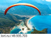 Paragliding in the sky. Paraglider tandem flying over the sea with blue water and mountains in bright sunny day. Aerial view of paraglider and Blue Lagoon in Oludeniz, Turkey. Extreme sport. Landscape. Paraglider tandem flying over the sea with blue water and mounta. Стоковое фото, агентство Ingram Publishing / Фотобанк Лори