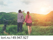 Young hipster couple holding hands walking on the meadow relaxin. Young hipster couple holding hands walking on the meadow relaxing and natural atmosphere is very natural. Стоковое фото, агентство Ingram Publishing / Фотобанк Лори