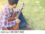 Young hipster man practiced guitar in the park,happy and enjoy p. Young hipster man practiced guitar in the park,happy and enjoy playing guitar. Стоковое фото, агентство Ingram Publishing / Фотобанк Лори