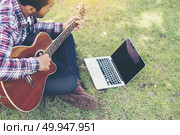 Young hipster man practiced guitar with laptop in the park,happy. Young hipster man practiced guitar with laptop in the park,happy and enjoy playing guitar. Стоковое фото, агентство Ingram Publishing / Фотобанк Лори