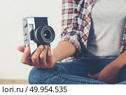 Young hipster photographer hand holding retro camera sitting on . Young hipster photographer hand holding retro camera sitting on wooden floor. Стоковое фото, агентство Ingram Publishing / Фотобанк Лори