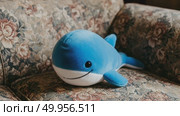Plush blue whale toy resting on floral sofa in cozy living room. Стоковое AI-видео, аниматор KATERINA AI / Фотобанк Лори