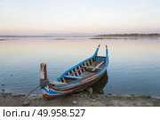 Wooden boat in Ubein Bridge at sunrise, Mandalay, Myanmar (World longest wooden bridge) Стоковое фото, агентство Ingram Publishing / Фотобанк Лори