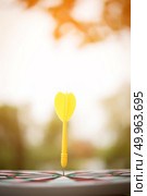 Yellow dart arrow hitting in the center of dartboard. Стоковое фото, агентство Ingram Publishing / Фотобанк Лори