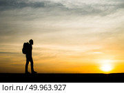 Silhouette of the young backpacker man walking  during sunset. Стоковое фото, агентство Ingram Publishing / Фотобанк Лори
