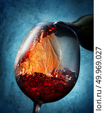 Wine pouring from bottle into a wineglass on blue background. Стоковое фото, агентство Ingram Publishing / Фотобанк Лори