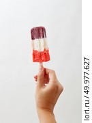A woman’s hand holds a colored berry ice cream lolly on a white background with copy space. Healthy food. Business concept concept. Cold natural colored berry ice popsicle , holds a female hand on a white background with space for text. A photo can be used for your business ideas. Стоковое фото, агентство Ingram Publishing / Фотобанк Лори