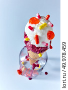 Waffle cone with fruity vanilla ice cream decorated with different capsules in a glass bottle on a blue background with drops of ice cream. Top view. Appetizing ice cream balls in a waffle glass with tablets capsules in a bottle on a blue background. Top view. Стоковое фото, агентство Ingram Publishing / Фотобанк Лори